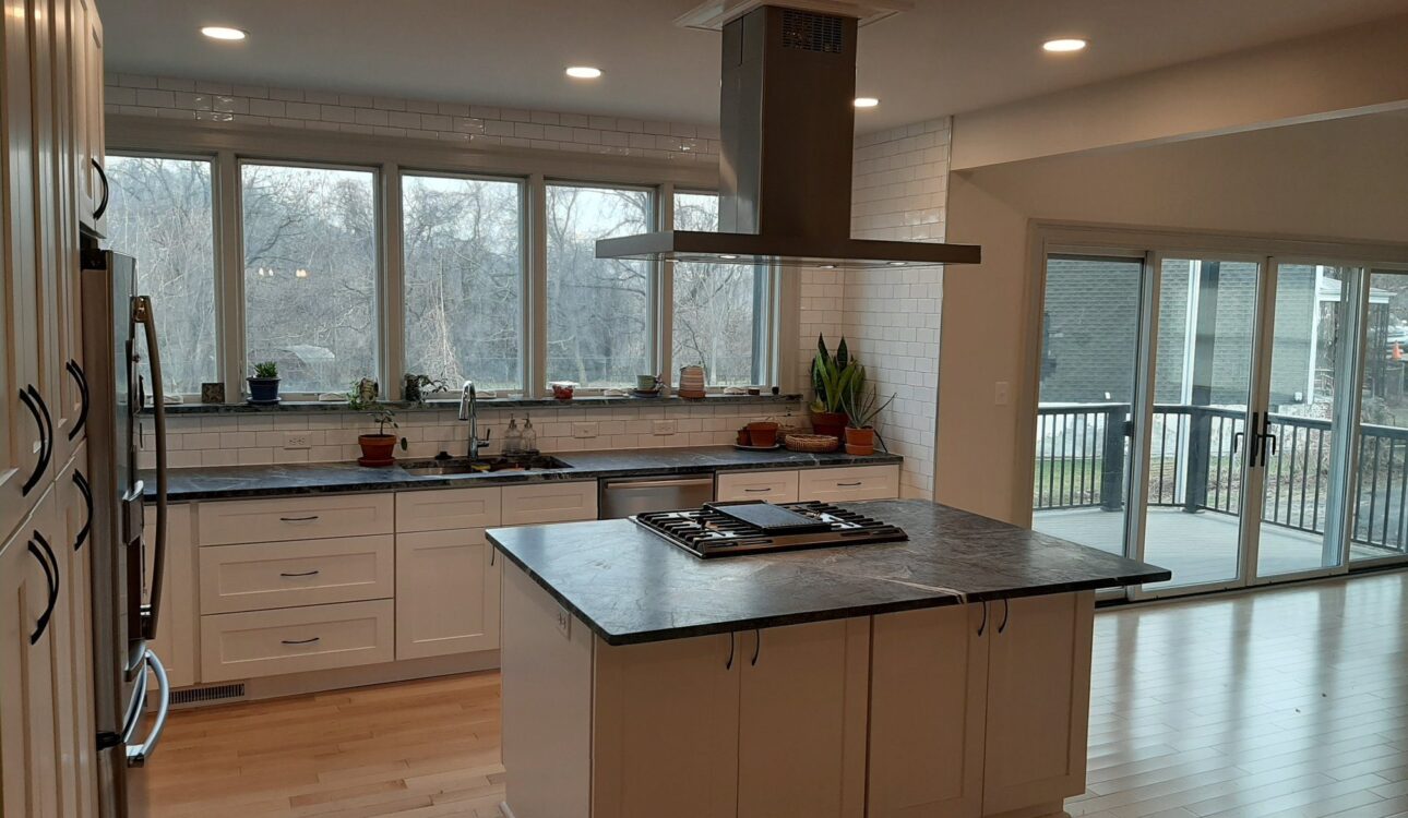 Modern kitchen interior featuring a spacious island with a stovetop, sleek cabinetry, large windows for natural light, and a contemporary design, ideal for maximizing space and functionality in Pittsburgh homes.