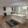 Modern basement interior showcasing waterproofing solutions, featuring a spacious layout with cabinetry, lighting, and a branded mat emphasizing JL Home Builders' services.