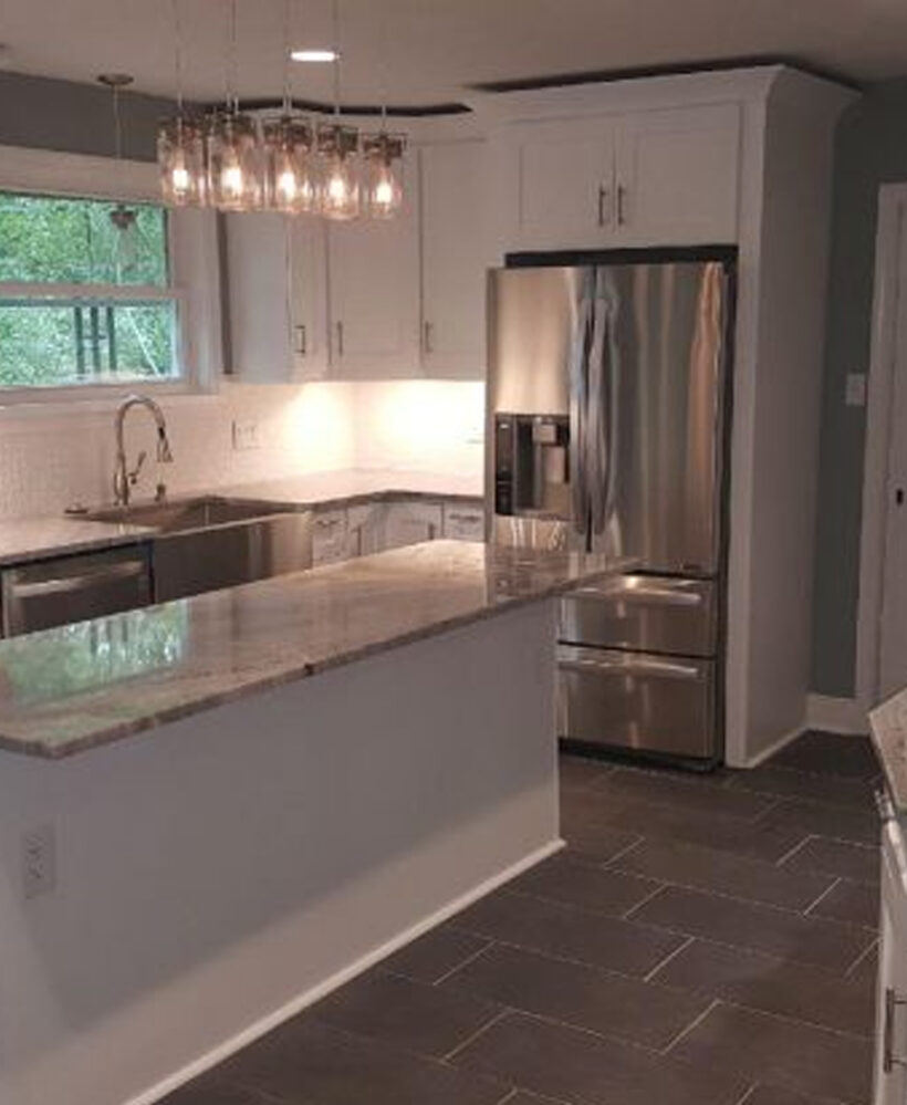 Modern kitchen with stainless steel appliances, granite countertop, white cabinetry, and pendant lighting, showcasing a stylish and functional space for home remodeling.