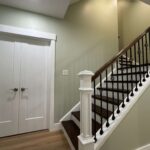 Staircase with wooden railing and white walls, leading to a second floor in a renovated Pittsburgh home, showcasing modern interior design suitable for home improvement projects.