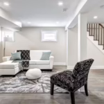 Finished basement living area with modern flooring, recessed lighting, seating, and an open staircase.