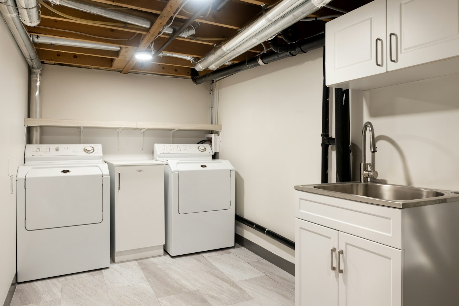 Finished basement laundry and utility area with washer, dryer, and sink