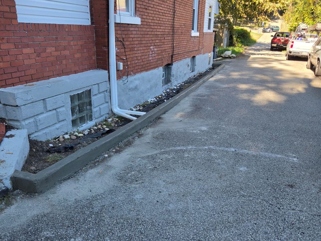 Freshly poured concrete curb along a brick house, JL Home Builders, Pittsburgh