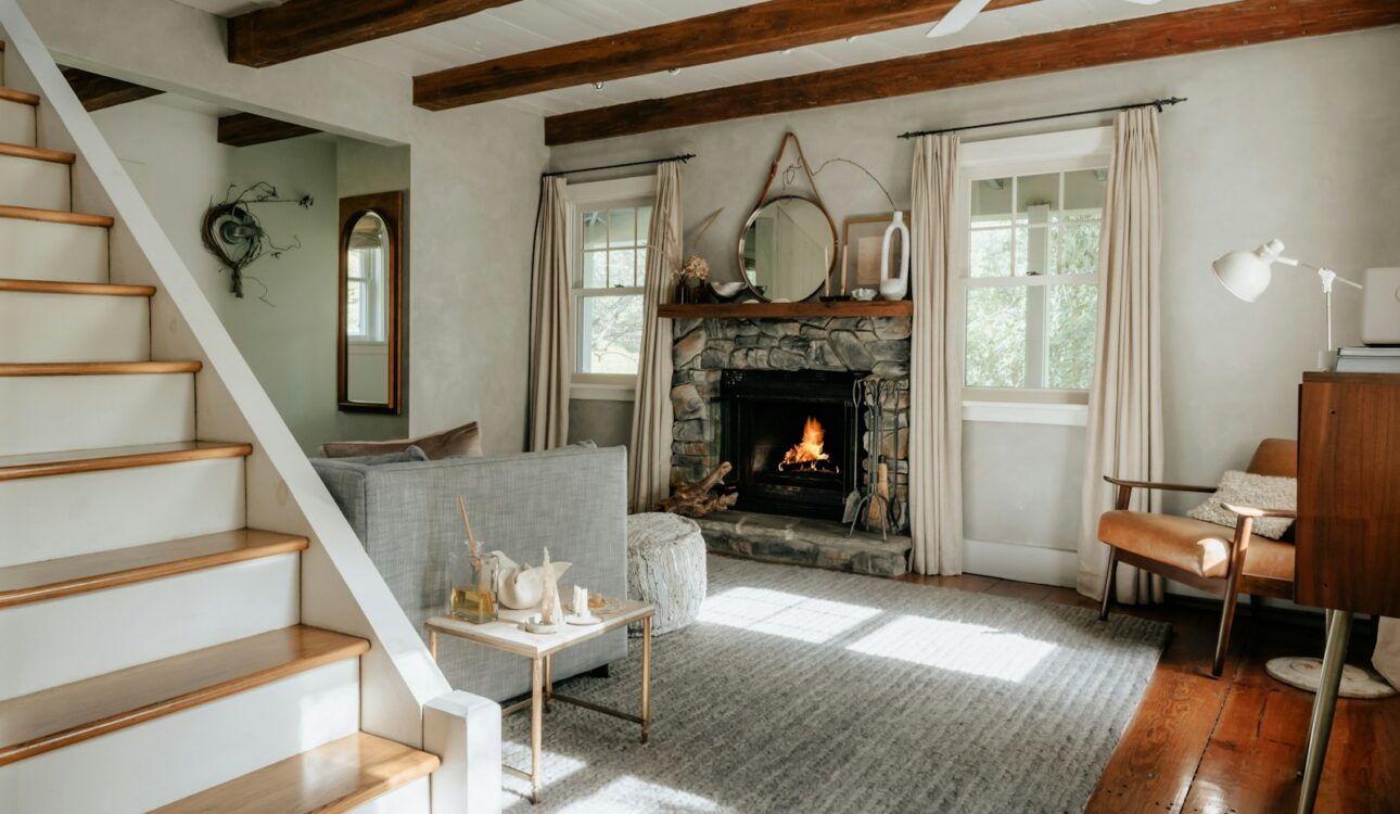 Living room with a fireplace, hardwood floors, and a staircase in an older home