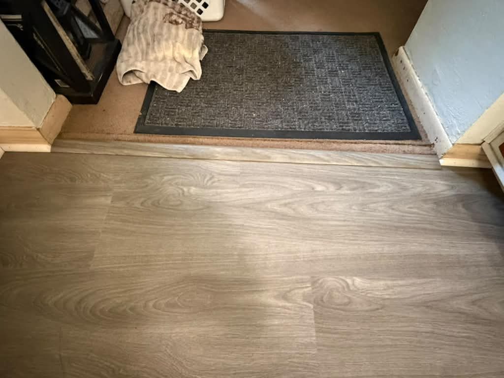 New vinyl plank flooring meeting an entry mat at a doorway, JL Home Builders, Pittsburgh