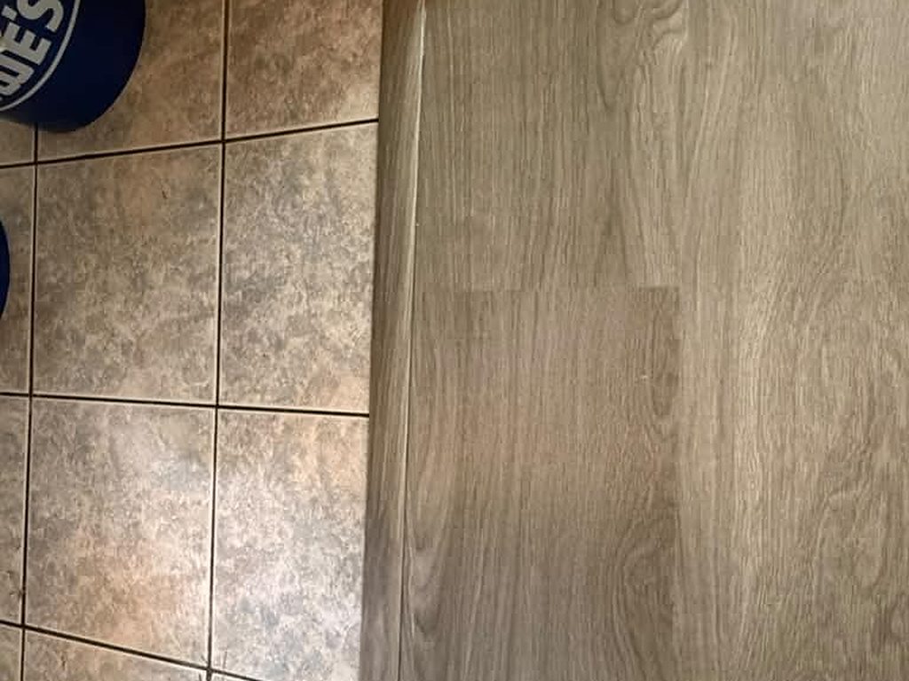 Close-up of a vinyl plank to tile transition strip, JL Home Builders, Pittsburgh