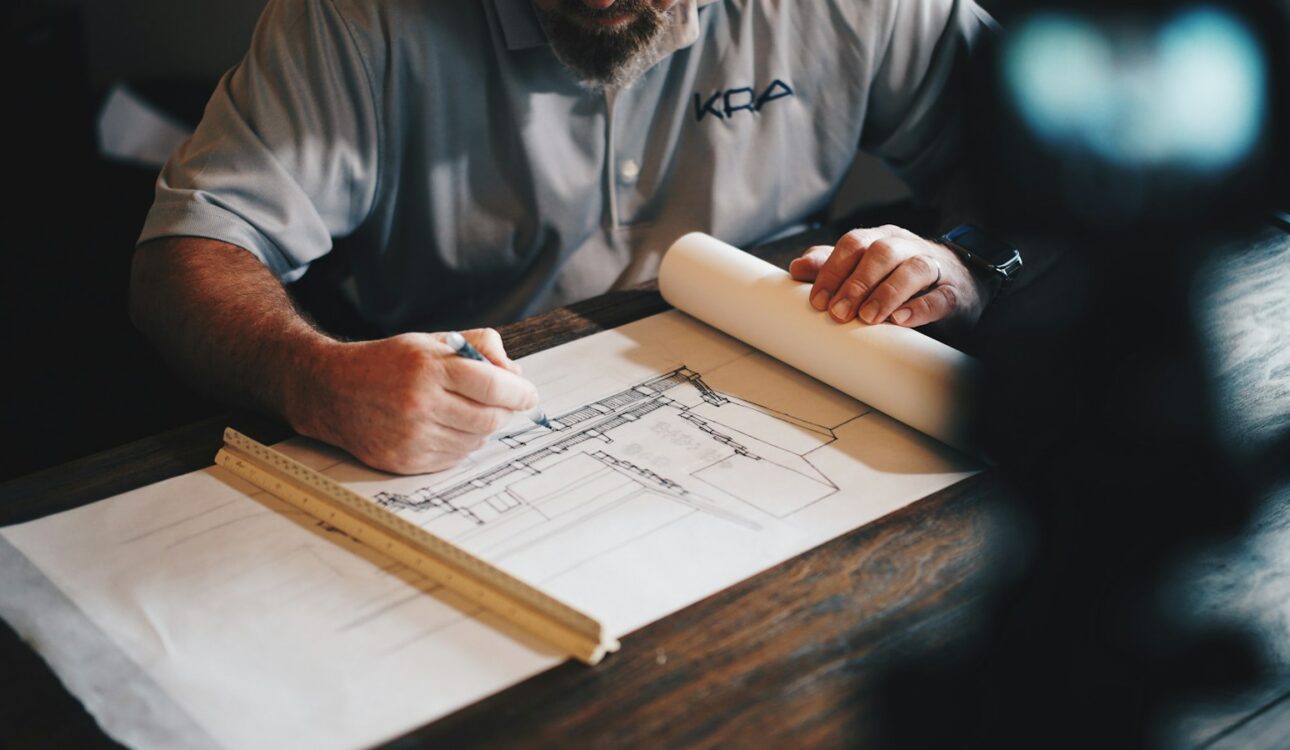 Hands reviewing home remodel plans on a table