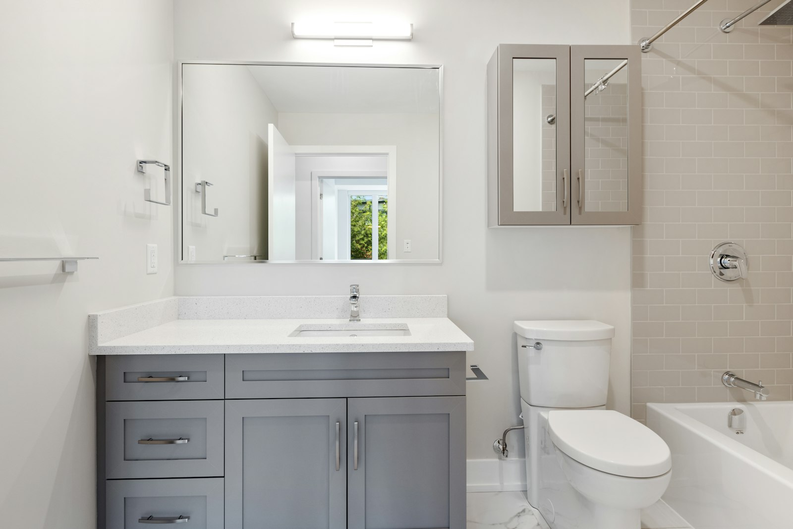 Updated bathroom with gray vanity, new toilet, and tub surround