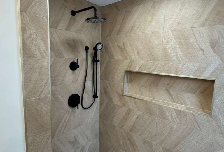 Walk-in shower with herringbone wall tile, a built-in niche and black fixtures