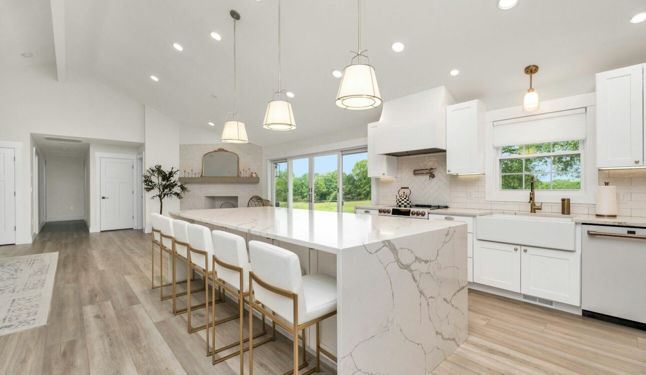 Large kitchen island with a waterfall stone edge, counter stools and pendant lights