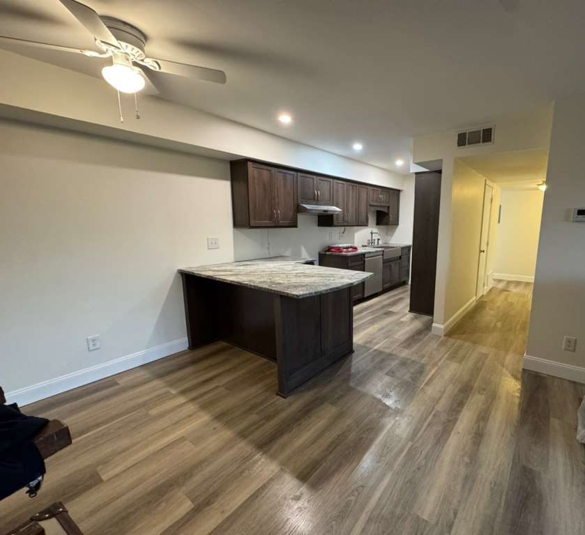 Open kitchen with dark wood cabinets, a stone peninsula and wood look floor, JL Home Builders, Pittsburgh