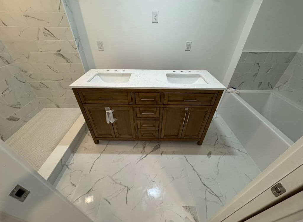 Primary bathroom with a wood double vanity and marble look floor tile, JL Home Builders, Pittsburgh