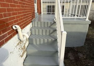 Back porch concrete restoration featuring refinished gray steps and custom white railing, enhancing safety and aesthetics on Crestline Street, Pittsburgh.