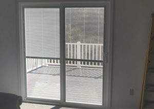 Sliding glass door leading to a two-tone composite deck with white railings, showcasing a modern outdoor living space designed by JL Home Builders.