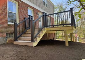 Raised deck with gray decking and black balusters in front of trees
