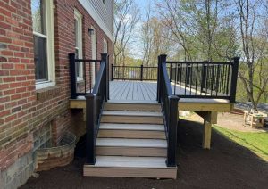 Wide deck stairs with black railings leading up to the deck