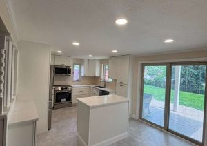 White kitchen with a center island, stainless appliances and sliding glass doors