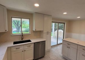 White kitchen with a sink under the window and a center island
