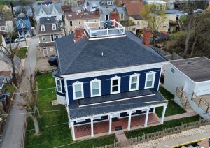 Complete roof replacement featuring premium architectural shingles and custom copper flashing on a renovated blue home in Mt. Washington, Pittsburgh, with a rooftop deck and surrounding residential area.