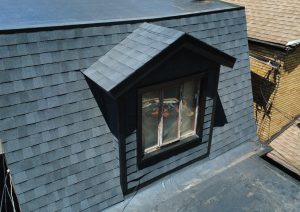 New shingles on a dormer and mansard roof next to a new flat roof