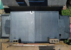 New black membrane roof on the main flat roof beside a chimney