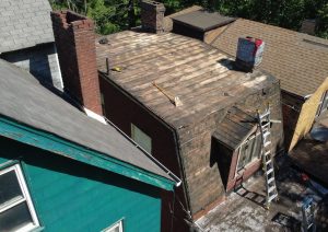 Roof deck with new plywood and the old roof removed around a chimney