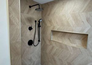 Walk-in shower with herringbone wall tile, a built-in niche and black fixtures