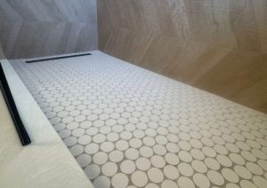 Penny round tile shower floor next to the hexagon bathroom floor