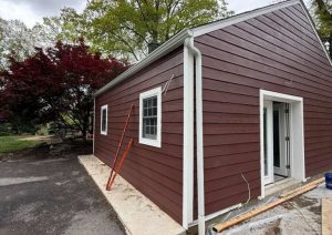 Side of a rear addition with red siding and a new entry