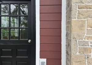 Black entry door with white trim beside a stone veneer pier