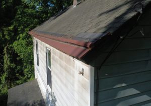 Crew removing old shingles and exposed boards at the edge of the roof