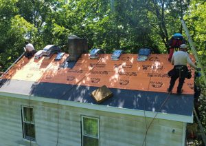 Orange underlayment and flashing installed along the ridge and chimney