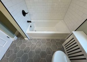 White subway tile tub surround with black curtain rod and robe hooks