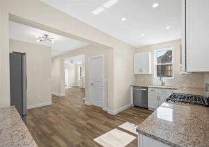 Modern kitchen interior with granite countertops, stainless steel appliances, and new flooring, showcasing a complete home renovation in Etna by JL Home Builders.