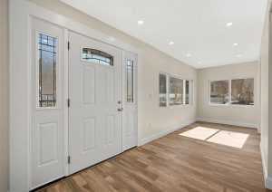 Bright entryway with white double doors, large windows, and modern lighting, showcasing new flooring and a spacious, clean design in a renovated home in Etna by JL Home Builders.