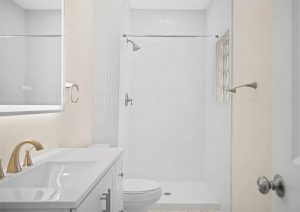 Modern bathroom with white fixtures, gold faucet, and glass shower door, showcasing a clean and bright renovation in an Etna home by JL Home Builders.