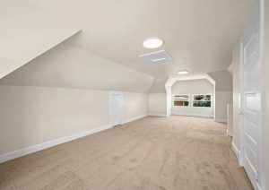 Bright, modern attic space with new carpet, fresh paint, and updated lighting, showcasing the transformation in a complete home renovation by JL Home Builders in Etna.