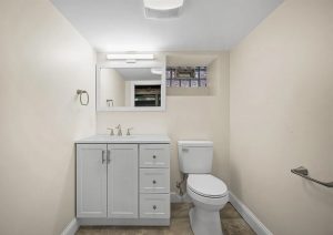 Modern bathroom renovation featuring a white vanity with storage, sleek sink, toilet, and neutral wall colors, showcasing a clean and bright space in a complete home renovation by JL Home Builders in Etna.