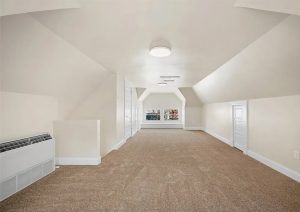 Spacious, newly renovated attic with neutral wall colors, modern lighting, and plush carpeting, showcasing the transformation of an outdated space in a complete home renovation by JL Home Builders in Etna.