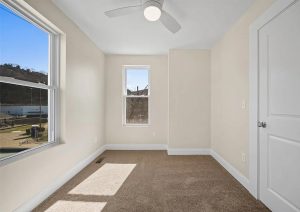 Bright, empty room with new carpet, modern ceiling fan, and large windows showcasing natural light, part of a complete home renovation in Etna by JL Home Builders.