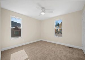 Bright, modern bedroom with neutral walls, plush carpet, and large windows showcasing natural light, part of a complete home renovation in Etna by JL Home Builders.