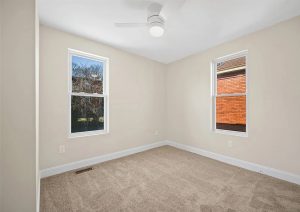 Bright, renovated bedroom with neutral walls, new carpet, and modern ceiling fan, featuring large windows for natural light, showcasing a complete home renovation by JL Home Builders in Etna.